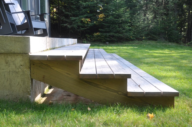 simple detail of deck steps down to the grass