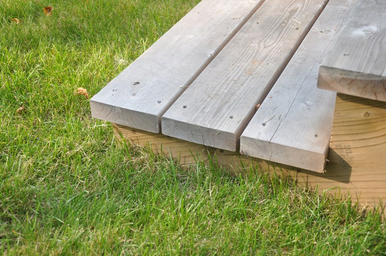 simple detail of deck steps down to the grass